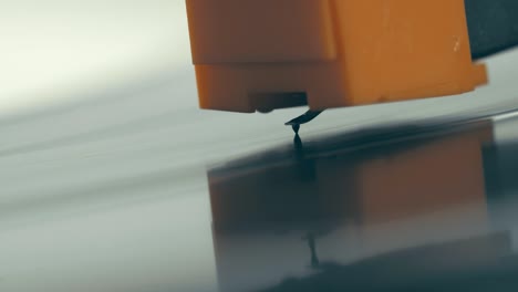 el lápiz con la aguja desciende suavemente y se eleva a un disco de vinilo negro giratorio. macro. vista lateral. el disco de vinillo en el reproductor de discos giratorio dj de cerca. el momento de una placa de vinilo giratoria