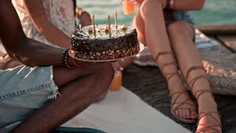 multi-ethnic friends having birthday party with cake on jetty