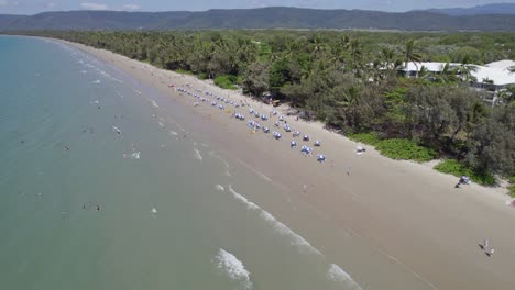 aerial view over four mile beach with people enjoying summer holidays in port douglas, australia - drone shot