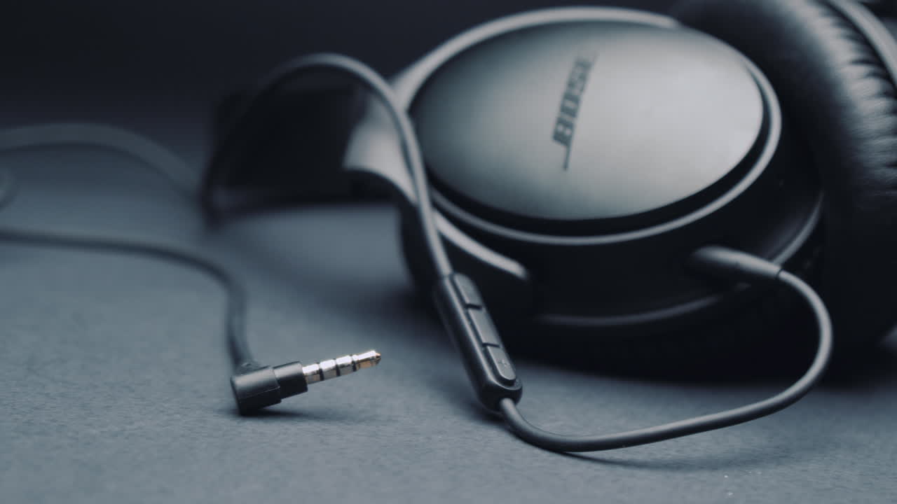 Black headphones BOSE on a pure gray background, the jack is in the foreground . Camera movement from left to right.