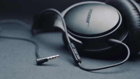 black headphones bose on a pure gray background, the jack is in the foreground . camera movement from left to right.