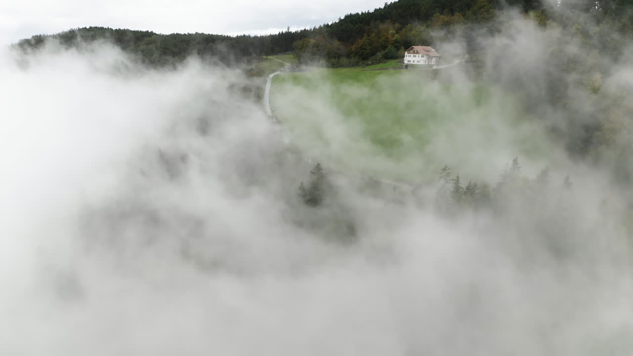 vista aérea que revela una carretera en medio de prados y bosques nublados en el tirol, italia