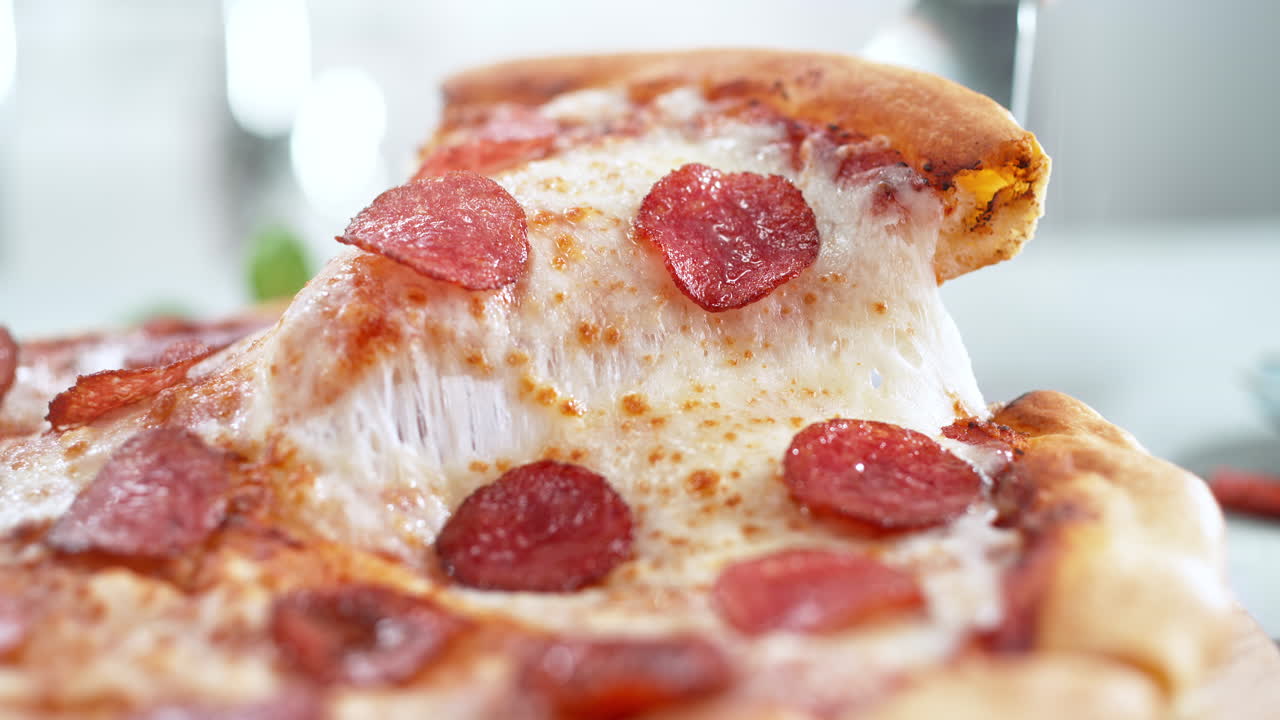 녹은 모차라 치즈, 매크로 및 느린 동작으로 인 페페로니 피자 조각을 들어 올리는 스파라