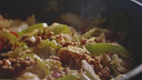 Pouring-sauce-in-homemade-mexican-food-and-mixing-it-all-with-a-wooden-spoon,-close-up-view