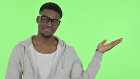 african man showing product in hand on green background