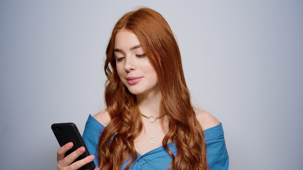 스튜디오에서 스마트폰을 들고 있는 아름다운 소녀. 실내에서 메시지를 읽는 여자