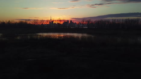 Slow-magic-hour-pan-of-serene-wetlands-with-city-skyline-in-the-distance