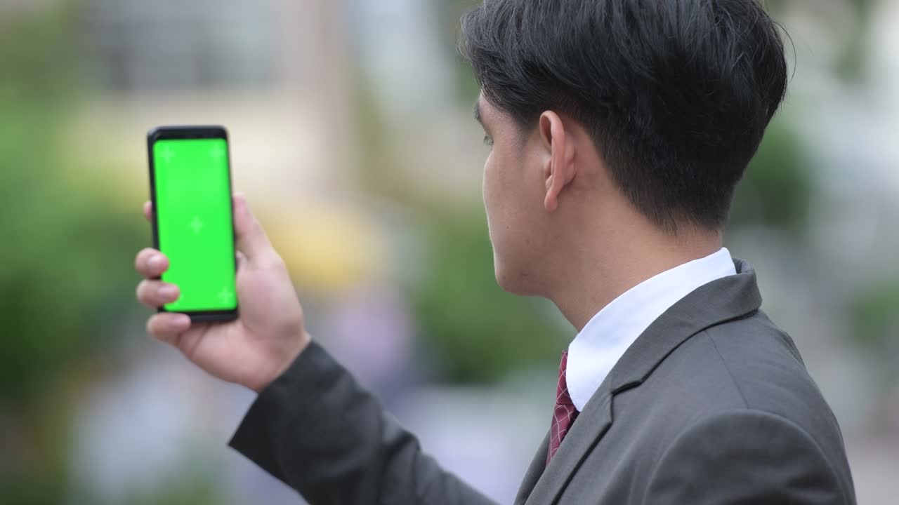 젊은 잘생긴 아시아 사업가들이 거리에서 드폰을 보여주고 있습니다.