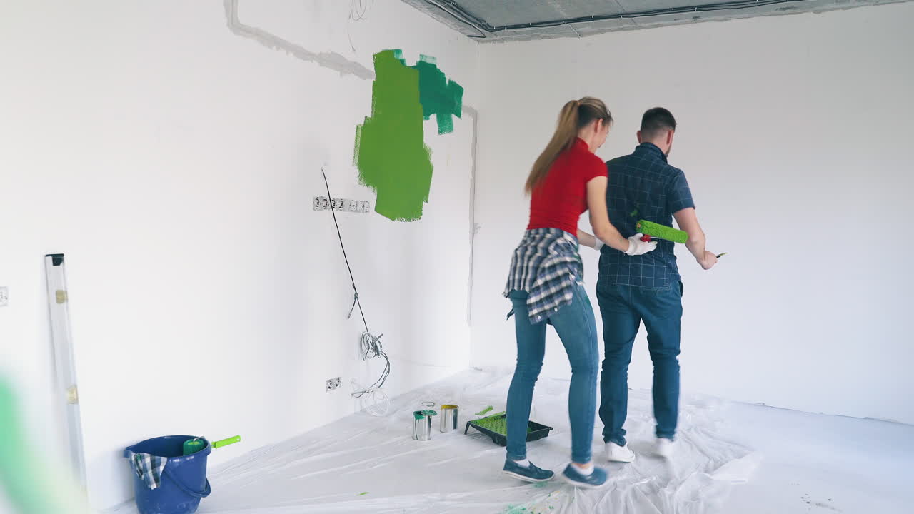 bailes familiares alegres pintando la pared blanca en una habitación moderna