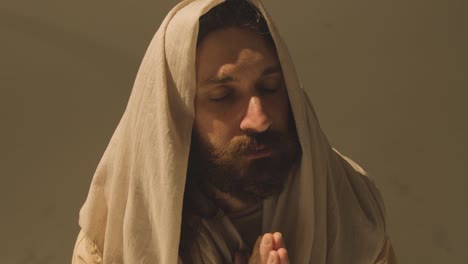 studio portrait of man wearing robes with long hair and beard representing figure of jesus christ praying 8