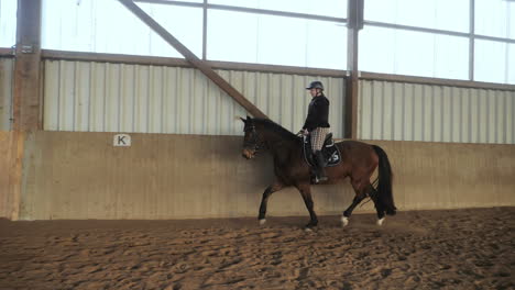 Slow-motion-shot-of-a-woman-riding-a-horse-in-riding-stablev