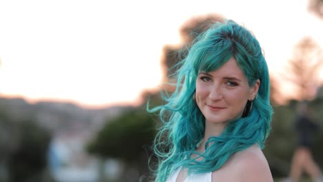 blue hair and bokeh, gen z woman with dimple smiling towards camera at twilight, copy space