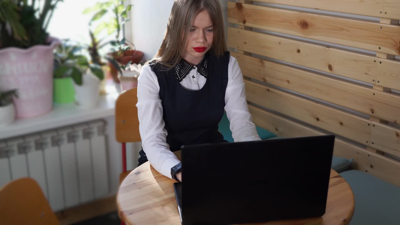 Молодая женщина работает на ноутбуке в кафе