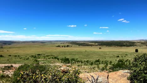 looking over a large expanse of green landscape with blue sky and clouds.