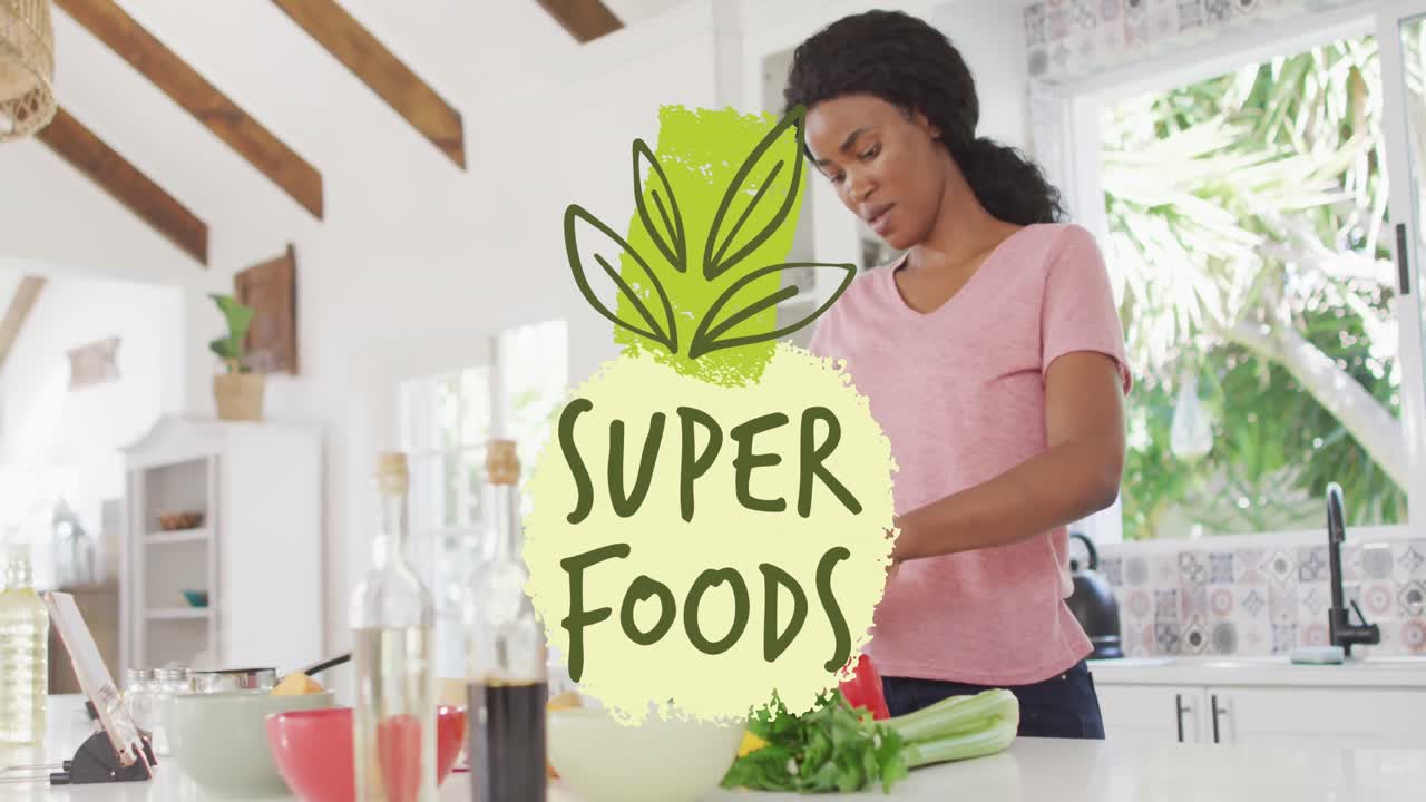 animación de hojas y súper alimentos texto sobre mujer afroamericana cortando verduras en la cocina