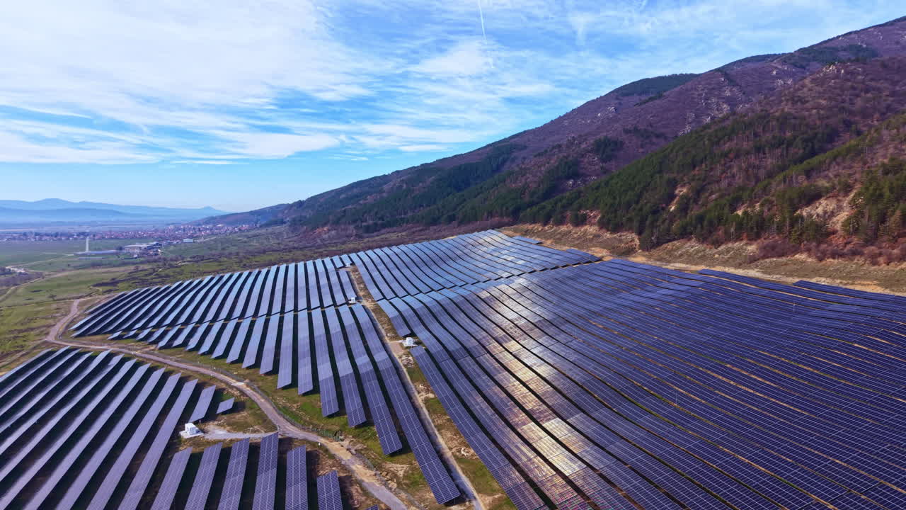 Solpaneler dækker landskabet nær bakker i dagtimerne i et vedvarende energiprojekt