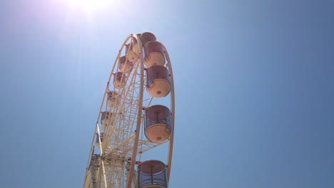 empty ferris wheel spinning under a bright sun during the day at darling harbour