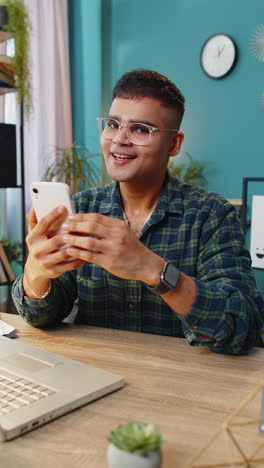 smiling young business man using smartphone online application pointing showing like thumbs up