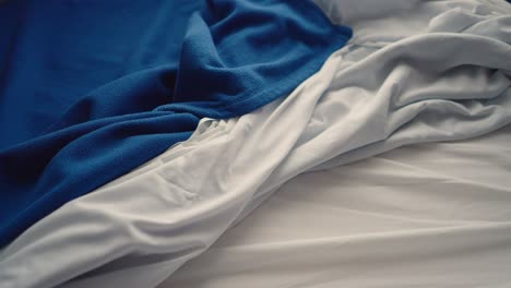 wrinkled bed sheet and blanket at a hotel room