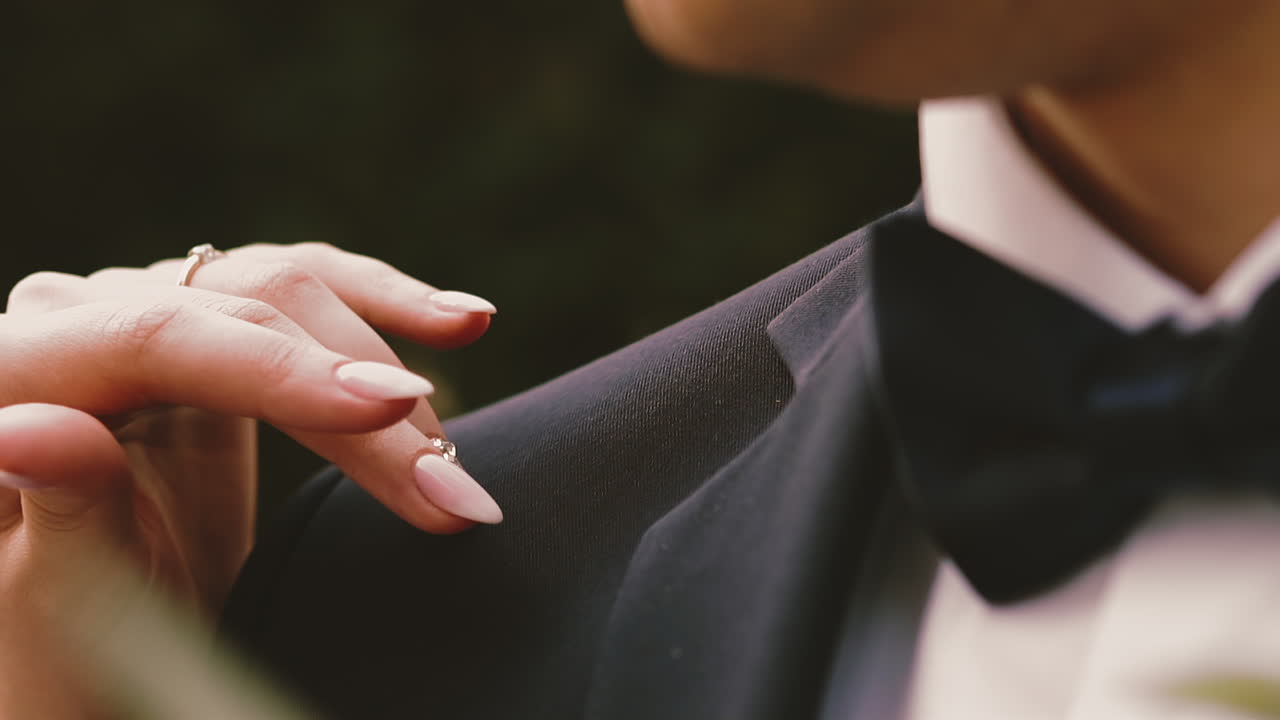la mano graciosa de la novia con el anillo de bodas acaricia el hombro del hombre