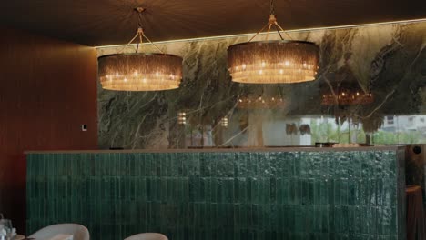 elegant interior with modern chandeliers and a green tiled counter in a stylish event space