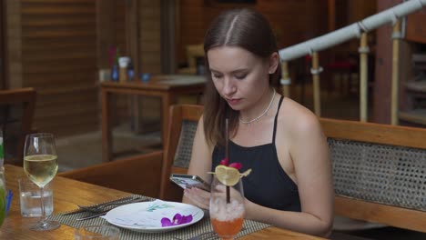 a static shot of a attractive young woman sitting in a cafe and looking at her smartphone