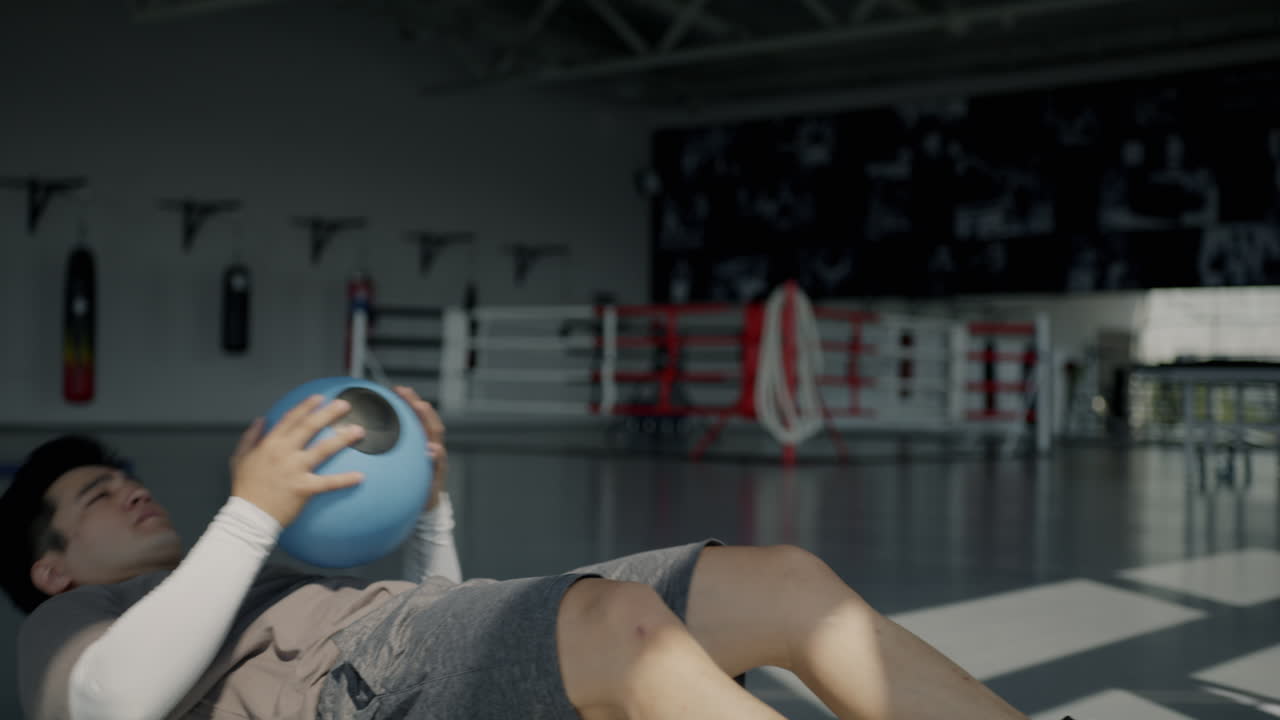 Man Doing Medicine Ball Sit-Ups in a Gym