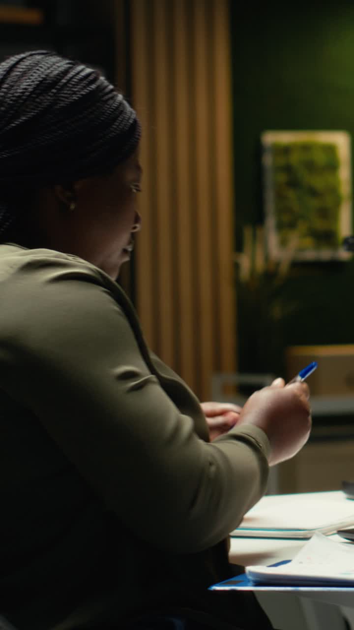 Vertical Video African american person documenting numbers and finance metrics