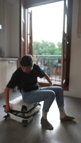 person packing a suitcase in a kitchen