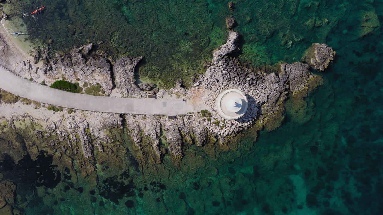 Overhead aerial view of Saint Theodore Lighthouse, Tourists kayaking in Kefalonia waters, Ionian Sea