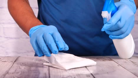 person cleaning a wooden table with spray bottle and cleaning cloth