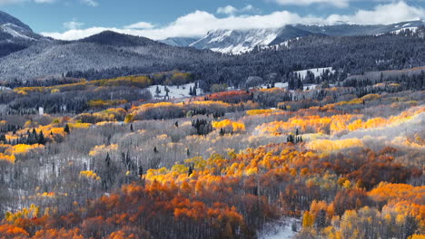 dramatic kebler pass crested butte colorado stunning fall winter first snow seasons collide aerial cinematic drone yellow aspen tree forest rocky mountains fog clouds lifting pan up forward motion