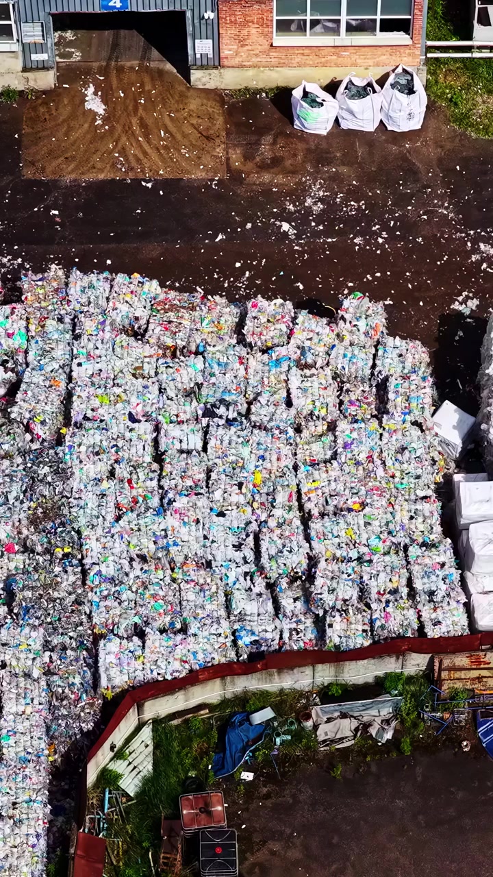 Aerial view of solar panels and large stacks of sorted recyclable waste outdoors