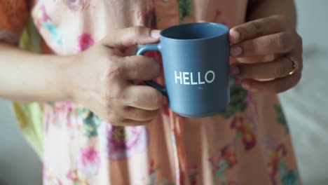 mujer sosteniendo una taza gris con la palabra hola