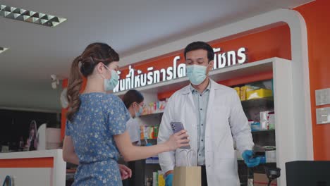 man cashier wearing a protective hygienic mask and glove scanning a barcode at a smartphone for contactless payment