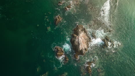 Vista-Aérea-De-Lapso-De-Tiempo-Rápido-Directamente-Sobre-Las-Olas-Del-Océano-Que-Se-Lavan-En-Las-Rocas-De-La-Costa-Debajo