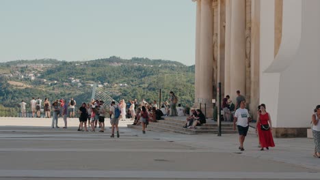 visitors explore coimbra university courtyard with distant mountain views, portugal