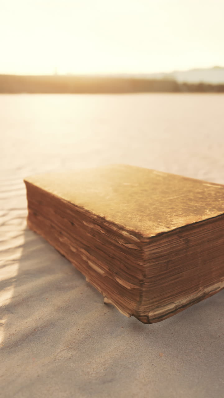 Vecchio libro su una spiaggia sabbiosa al tramonto