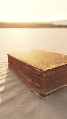 old book on a sandy beach at sunset