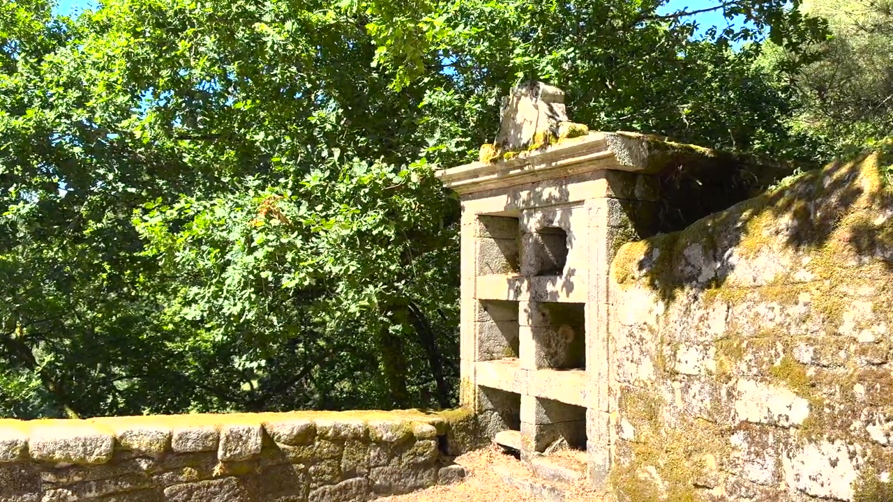 Struttura a nicchia in pietra tra gli alberi a San Pedro de Rocas a Esgos, Ourense, Galizia, Spagna.