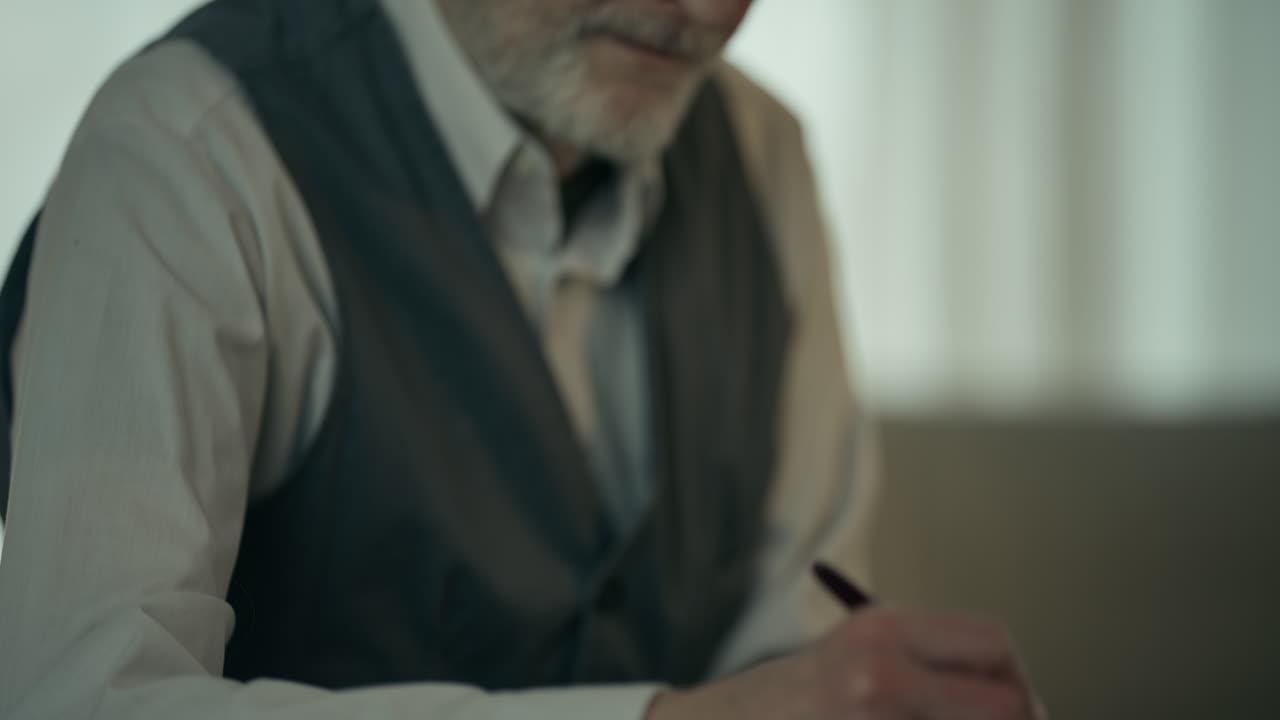 Primo piano di un uomo anziano che scrive su un quaderno.