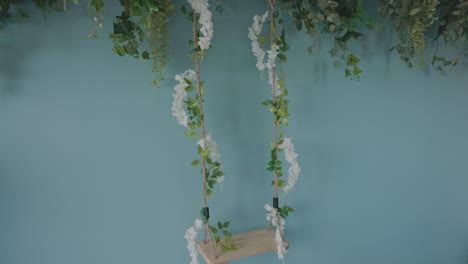 wooden swing decorated with artificial flowers hanging by the wall inside beauty salon