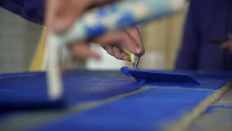 close up shot of professional artisan spreading carefully blue tint with trowel