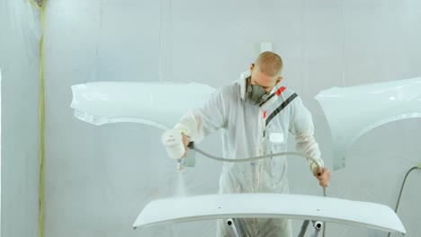 mecánico pintando piezas de automóviles con una pistola de pulverización eléctrica 4k