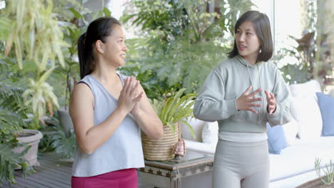 happy asian female friends stretching and smiling on sunny terrace, slow motion