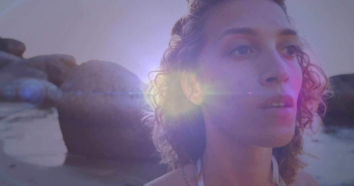 Woman showcasing marketing on rocky coast, overlaying animated lens flare data and necklace icons