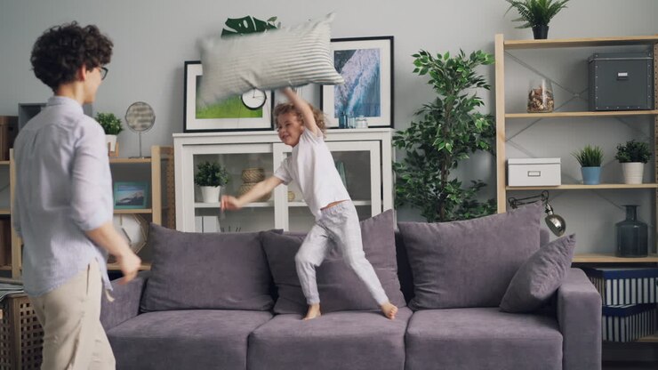 Mother and son having a pillow fight at home
