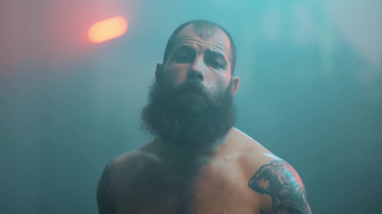 Ritratto intenso di un uomo barbuto con tatuaggi e illuminazione drammatica