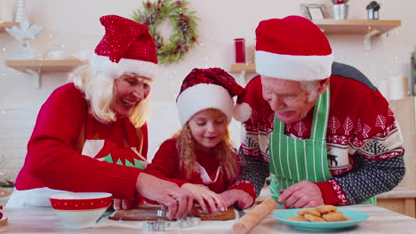 senior family grandmother, grandfather, granddaughter preparing, cooking homemade christmas cookie