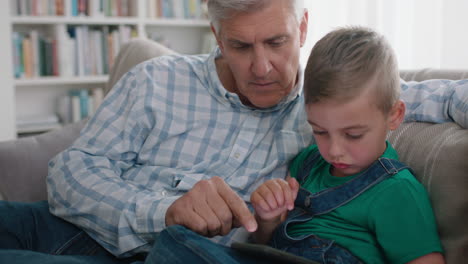 happy grandfather showing little boy how to use smartphone teaching curious grandson modern technology intelligent child learning mobile phone sitting with grandpa on sofa